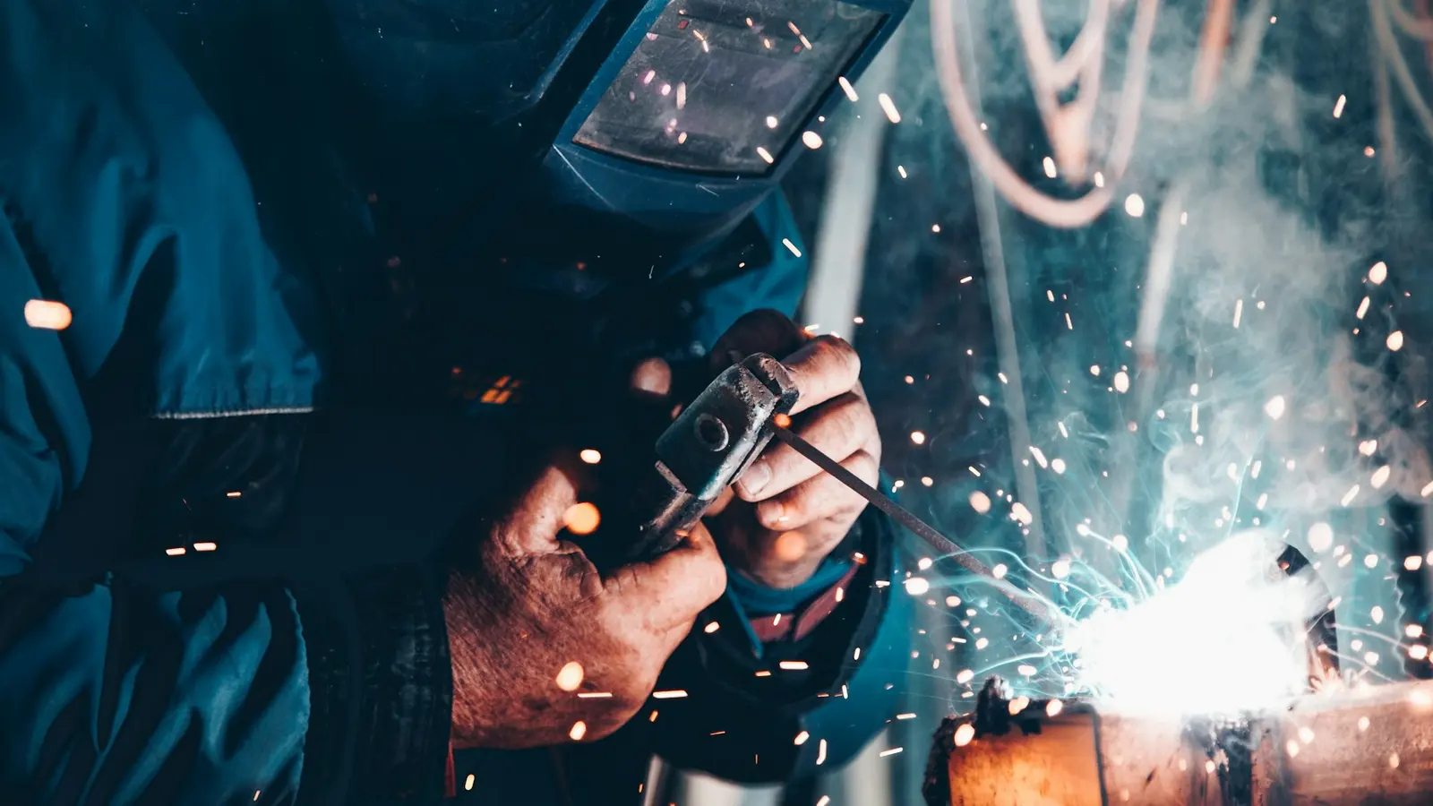 Ein Handwerker schweißt, beide Hände am Werkstück.